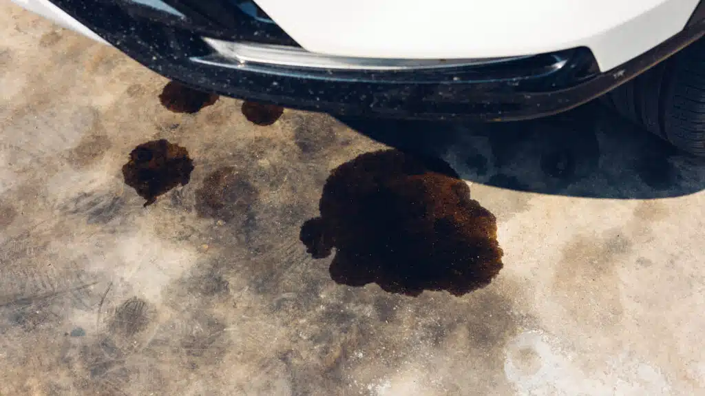 engine oil leakage on concrete floor. Black engine oil on concrete floor. Engine oil leak from the engine. surface concrete with the motor oils stain grey black silver.